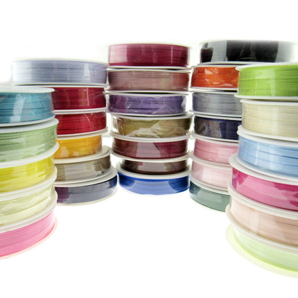 A collection of double faced satin ribbons in various colors, each ribbon is 3mm wide and 50 meters long, displayed in a stacked arrangement.