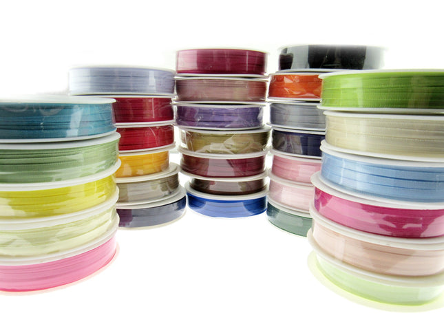 A collection of double faced satin ribbons in various colors, each ribbon is 3mm wide and 50 meters long, displayed in a stacked arrangement.
