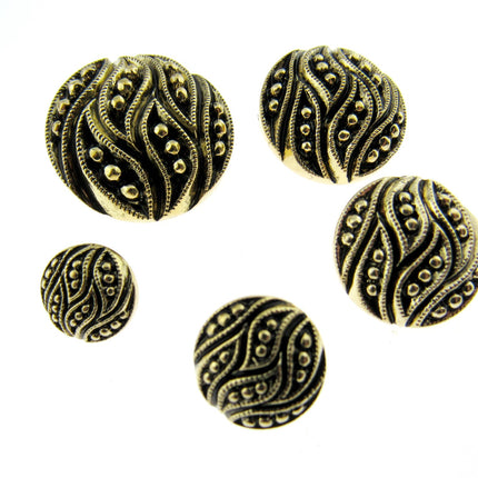 A set of ornate, round, gold leaf buttons in varying sizes displayed on a neutral surface.
