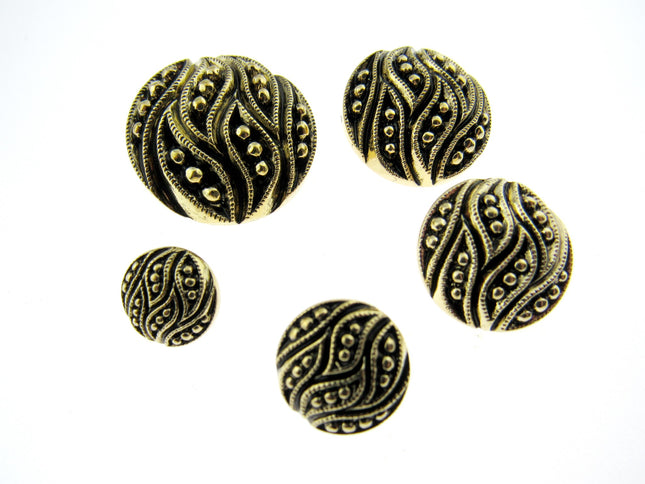 A set of ornate, round, gold leaf buttons in varying sizes displayed on a neutral surface.
