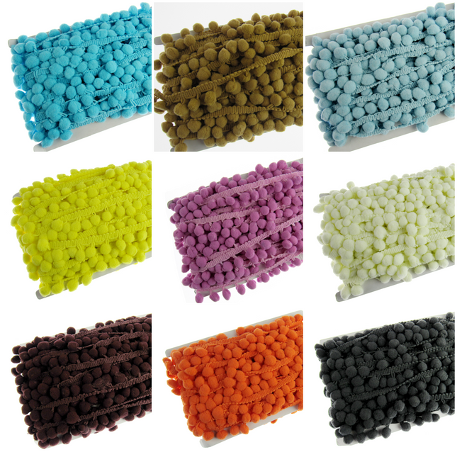A collection of pom pom trimmings in various solid colors including blue, brown, gray, green, purple, yellow, pink, white, black, and orange.